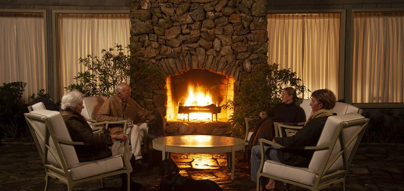 Beaufort Club Chairs around an outdoor fireplace at nighttime