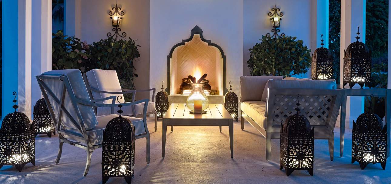 Beaufort Club Chairs and Wyatt Coffee Table on a patio at nighttime with candles lit and an outdoor fireplace