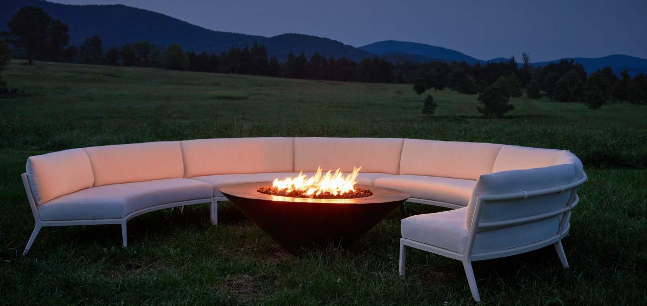 deCamp Lune Sectional around an outdoor firepit in a field at dusk