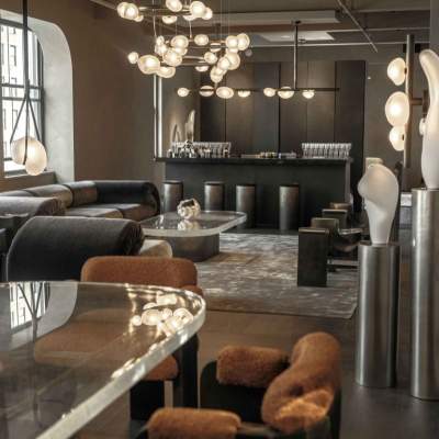 A modern luxury showroom featuring plush curved armchairs, sleek metallic lighting fixtures, and decorative glass objects.