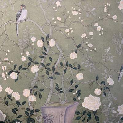 Close-up of hand-painted floral wallpaper with white blossoms, green leaves, and a perching bird on a grey background.
