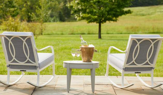 McKinnon and Harris Buie Rocking Chairs and a small side round side table with a bottle of wine overlooking a lush backyard