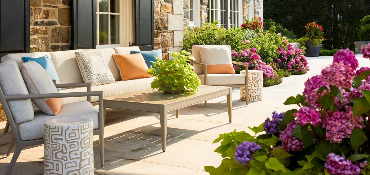 McKinnon and Harris deCamp Club Chairs and Sofa paired with a Wyatt Rectangular Coffee Table under a covered garden space. Design by Cullman & Kravis.