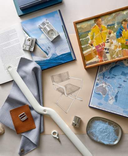 McKinnon and Harris Flat lay arrangement featuring an outdoor armchair sketch, fabric samples, leather swatch, framed nautical artwork, map, camera, and decorative accents.