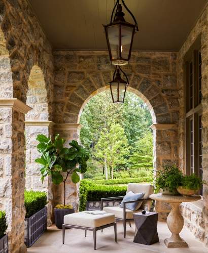 McKinnon and Harris deCamp Club Chair on a covered stone terrace at a home in Atlanta, Georgia. Design by Suzanne Kasler