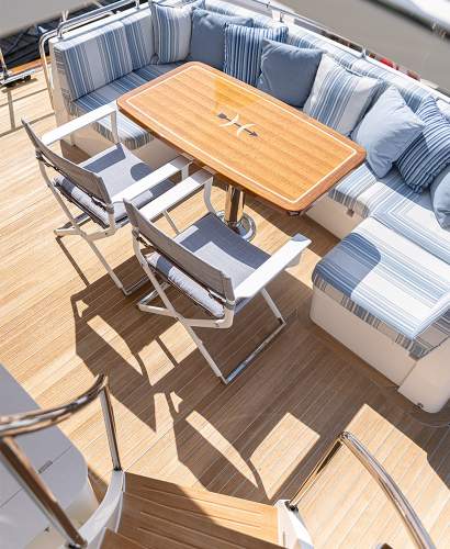 McKinnon and Harris Scout Folding Yacht Chair finished in Classic White with Italian Performance Fabrics pulled up to a table on a yacht deck