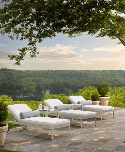 Rives Sun Chaises finished in York River Oyster on a stone patio overlooking a lush vista