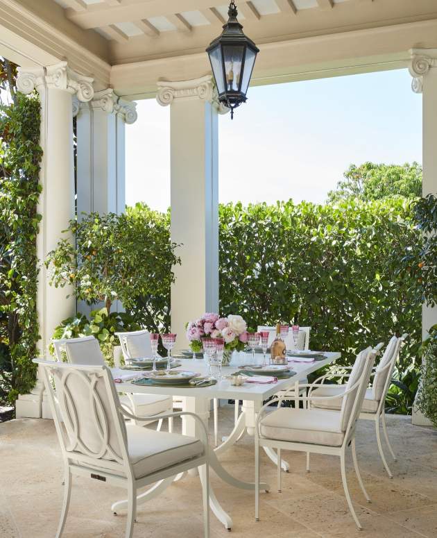 Buie Dining Chairs and Dining Table under a loggia with pink flowers. Design by William Eubanks.