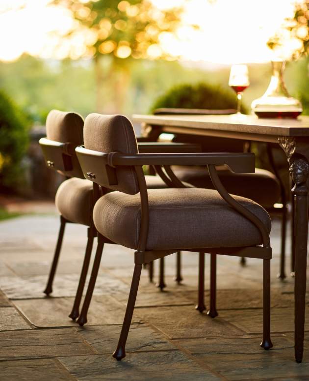 Close-up detail of the Bastille Dining Arm Chair in Jura Peat finish highlighting the unique skeleton key-shaped armrest and curved aluminum frame.