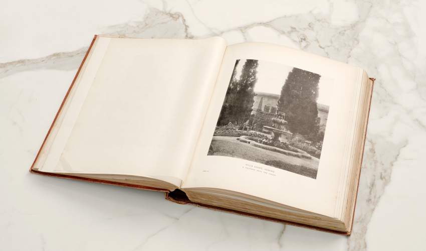 A book placed open to a page with a black and white photograph of a fountain