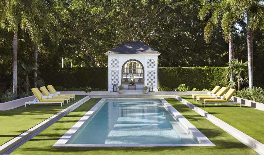 McKinnon and Harris duVal Sun Chaises in a bright yellow fabric poolside at a home in Florida. Design by Carrier and Co.