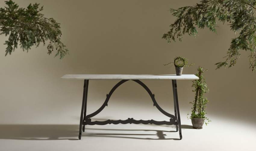 Campostela Console Table Shown in Natural Bronze with Calacatta Michelangelo Extra Natural Stone Top styled with plants around it and on it