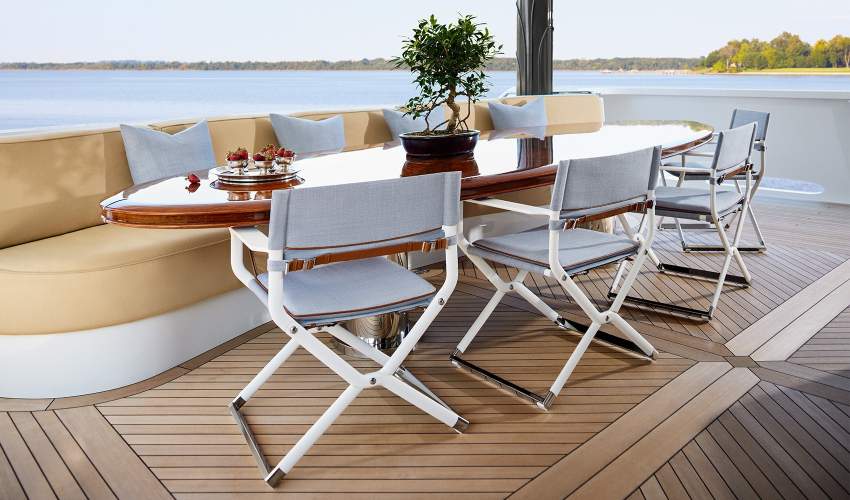 McKinnon and Harris Scout Folding Yacht Chair finished in Classic White with Italian Performance Fabrics pulled up to a dining table on a Yacht.