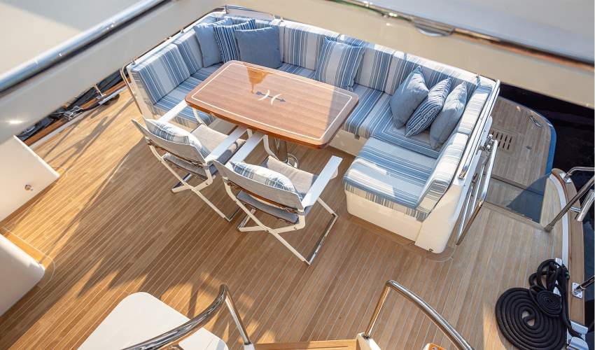 McKinnon and Harris Scout Folding Yacht Chair finished in Classic White with Italian Performance Fabrics pulled up to a table on a yacht deck